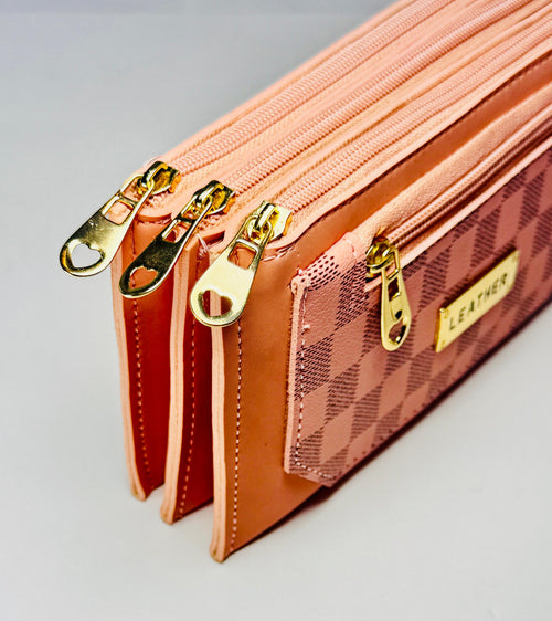 Close-up of a pink leather wallet with gold zippers on a light gray background